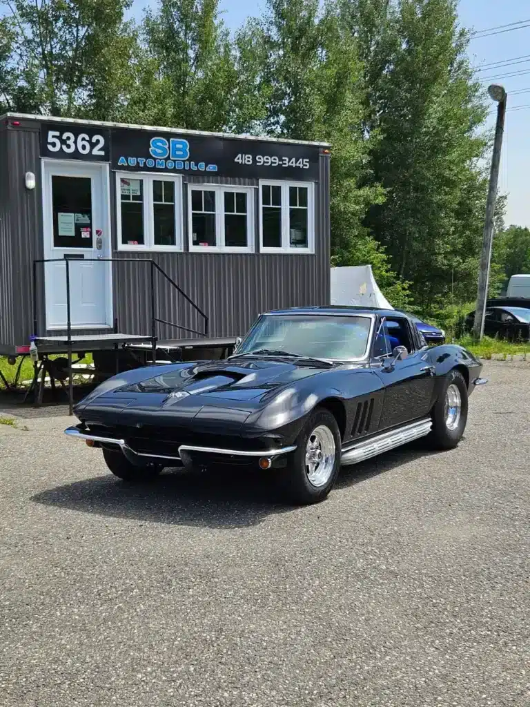 Black 1965 Chevrolet Corvette Sting Ray parked outside SB Automobile dealership.